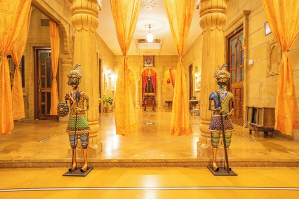 A grand hallway with ornate columns and golden drapes.