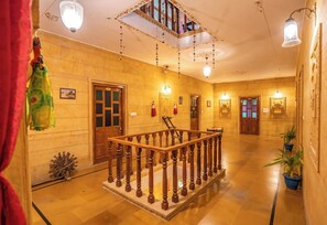 Un passadís d'hotel amb una escala de fusta, portes i decoracions penjants.
