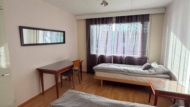 Una habitación con cama, escritorio y silla.