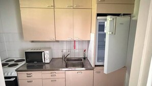 Cocina compacta con microondas, estufa, pileta y refrigerador.