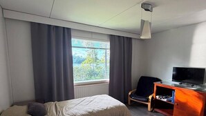 Habitación de hotel con dos camas, televisión, escritorio y ventana con cortinas.
