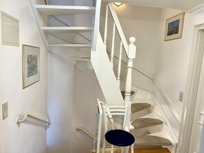 A white staircase with a handrail, a chair, and a picture on the wall. - Süderstraße 29a, Apt. 02 - 3-room upper-floor vacation apartment with a south-facing balcony for (Sylt-Ost)