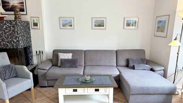 A living room with a grey sectional sofa, a white coffee table, and a fireplace. - Norderstraße, Apartment 1 - Cozy ground-floor vacation apartment with a fireplace and (Sylt)