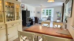 A dining area with a wooden table and white chairs, a kitchen with a marble countertop, and a living area with a sofa and armchairs. - Norderstraße, Apartment 1 - Cozy ground-floor vacation apartment with a fireplace and (Sylt)