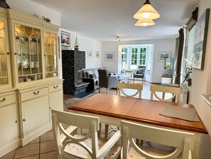 A dining area with a wooden table and white chairs, a kitchen with a marble countertop, and a living area with a sofa and armchairs. - Norderstraße, Apartment 1 - Cozy ground-floor vacation apartment with a fireplace and (Sylt)