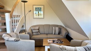 A modern living room with a sofa, two armchairs, a coffee table, and a floor lamp. - Eidumweg Apartment 4 - Bright and modern upper-floor apartment for 4 people with (Sylt)