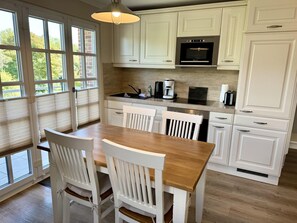 A kitchen with white cabinetry, a wooden dining table, and chairs. - Eidumweg Apartment 4 - Bright and modern upper-floor apartment for 4 people with (Sylt)