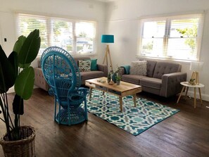 Ein Wohnzimmer mit einer Couch, einem Couchtisch, einem blauen Sessel und einem gemusterten Teppich.