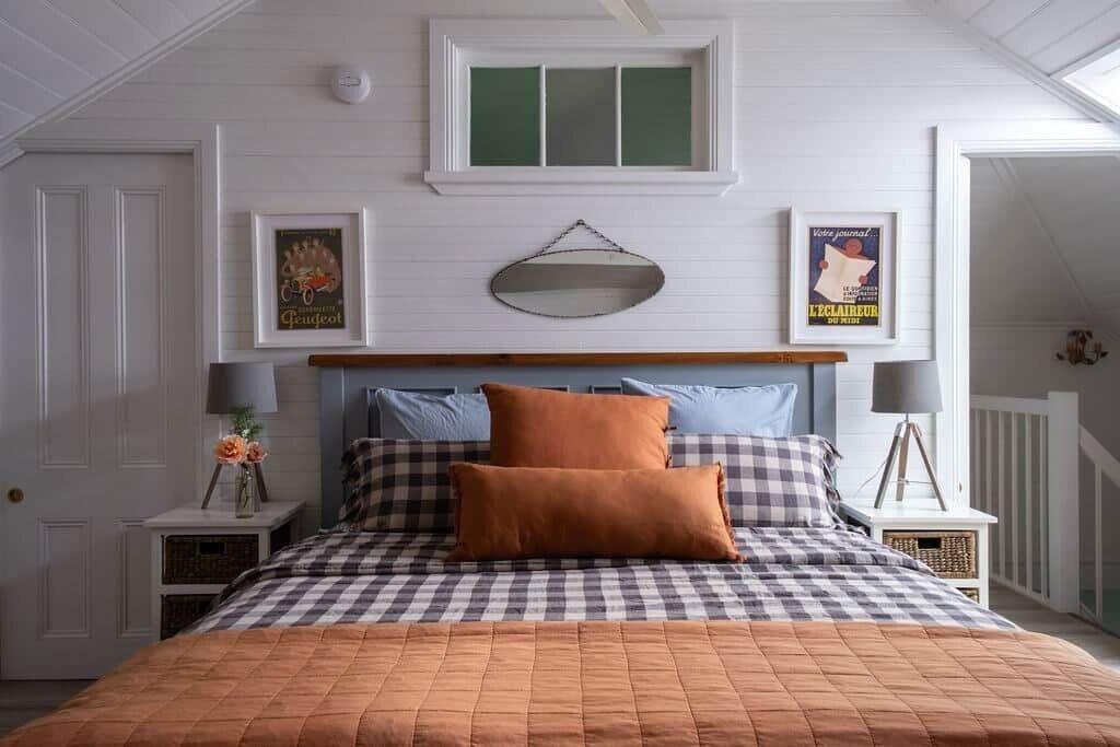 A bedroom with a checkered bedspread, a wooden headboard, and a window above the bed.