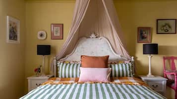 A bed with a canopy, striped bedding, and two bedside lamps.