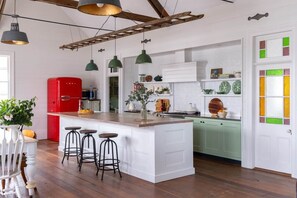 A kitchen with a central island, bar stools, a red refrigerator, and a green cabinet.