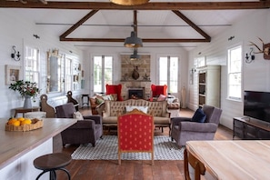 A spacious living room with a fireplace, a dining area, and a kitchen visible in the background.
