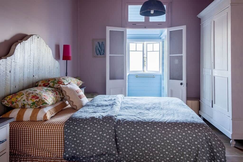 Ein Schlafzimmer mit Bett, Nachttisch, Lampe, Kleiderschrank und Fenster.