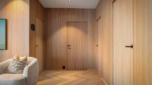 A hallway with wooden paneling, a door, and a chair with a cushion. - New Luxury Designer Cabin in Lofoten (Nordland)