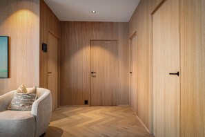 Ein Korridor mit Holzwänden, einer Tür und einem Sessel mit Kissen.
