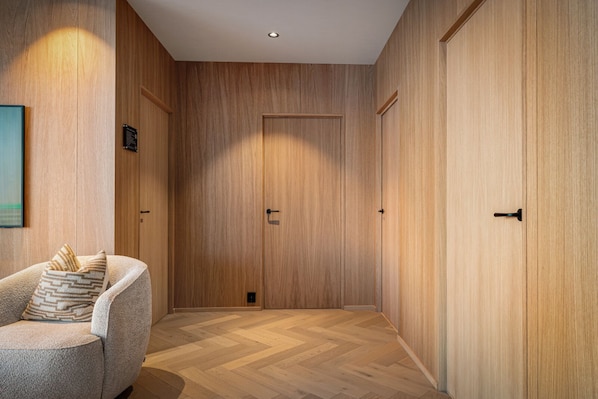 Un couloir avec des lambris en bois, une porte et une chaise avec un coussin.