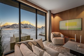 A modern living room with a large window overlooking a snowy landscape.