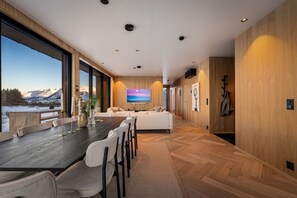 Ein modernes Interieur mit einem großen Esstisch, Sitzgelegenheiten, einer Couch und einem Fernseher.