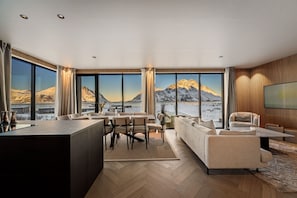 Un salon moderne doté d’une grande fenêtre donnant sur un paysage montagneux.