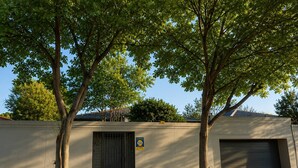A building with a gated entrance, a garage door, and a small garden area with a paved walkway.