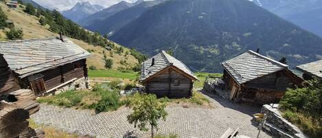 Un pueblo de montaña con casas de madera tradicionales, senderos de piedra y vistas a montañas distantes.