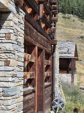 Eine rustikale Holzhütte mit Steinwänden und Holzbalken, mit einem kleinen Fenster und einer Tür.