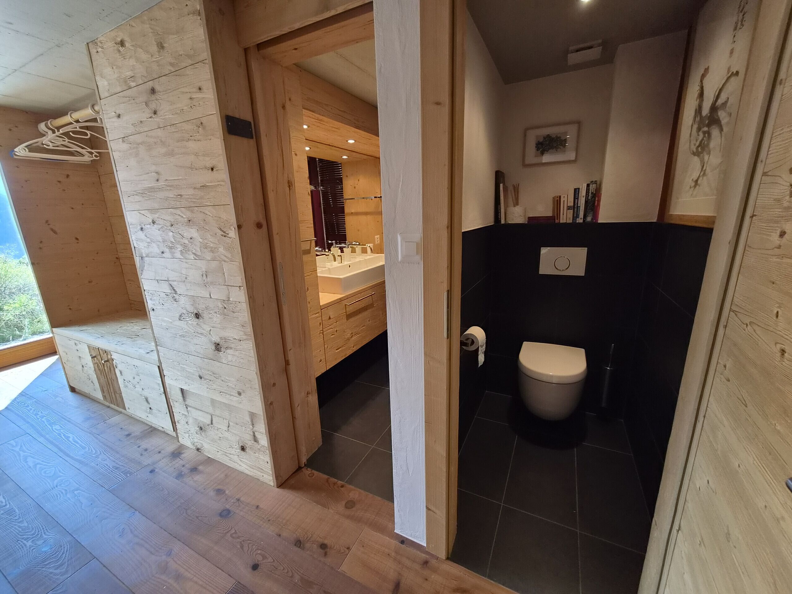 A wooden interior with a visible bathroom, including a toilet and sink area.