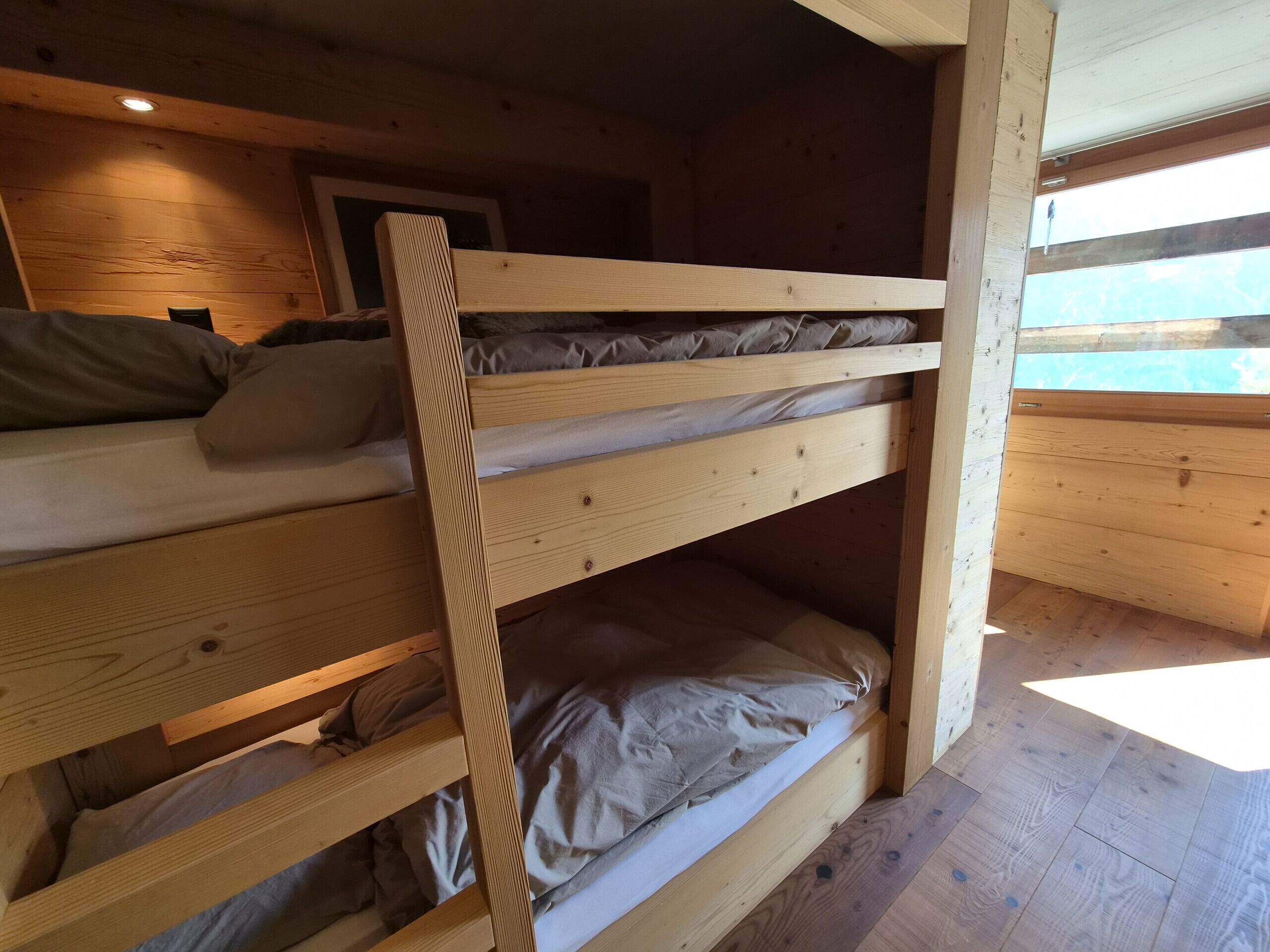 A bunk bed room with wooden walls and a window.