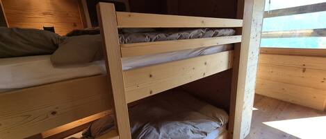 A bunk bed room with wooden walls and a window.