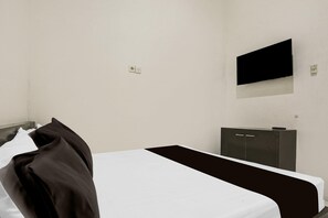 Habitación de hotel con una cama, televisión en la pared y un mueble pequeño.