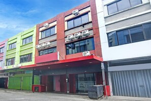Un edificio de varios pisos con locales comerciales en la planta baja, con amplias ventanas y unidades de aire acondicionado.