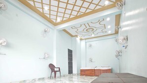 A spacious room with a marble floor, a wooden bench, and a ceiling with a grid pattern. - Khushi Home Stay (Varanasi)