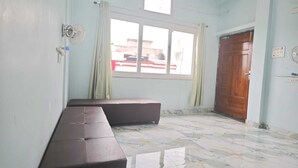 A room with a bench, a window, a door, and a ceiling fan. - Khushi Home Stay (Varanasi)