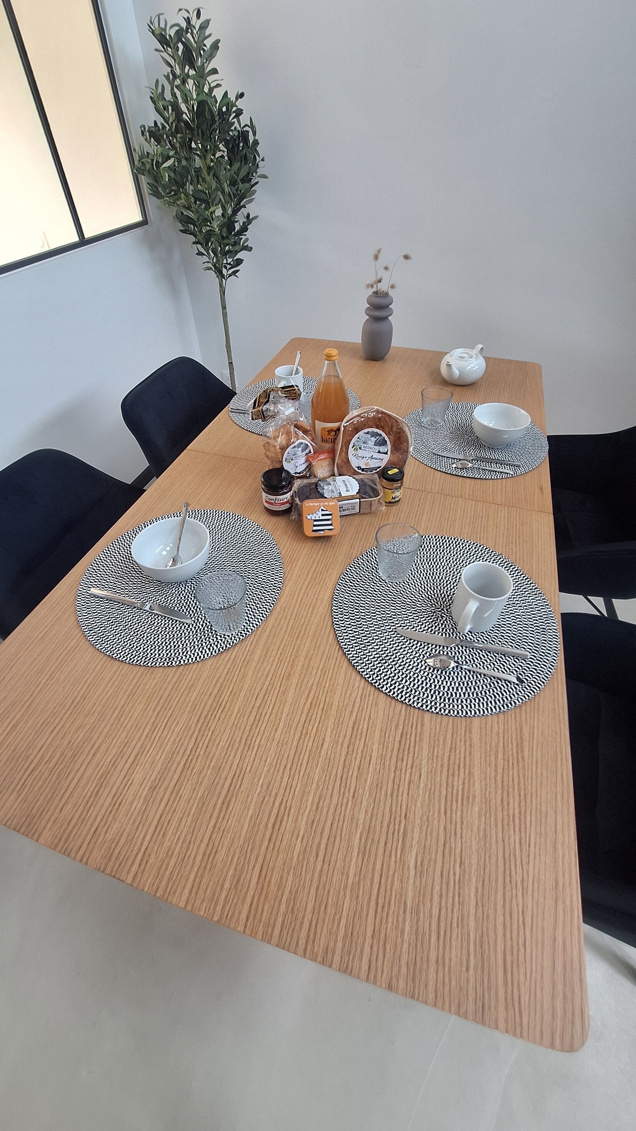 Ein Esstisch mit Platzsets, Besteck, einer Flasche und einer Vase mit Trockenpflanzen.