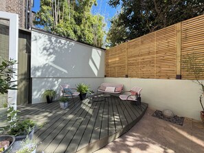 A deck with outdoor furniture, a wooden fence, and potted plants. - Beautiful 2BDR Home Right by Regents Park (Greater London)