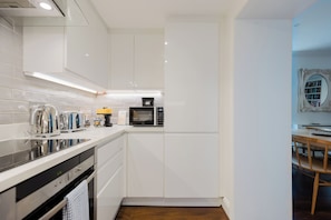 A compact kitchen with white cabinets, a microwave, and a coffee machine. - Beautiful 2BDR Home Right by Regents Park (Greater London)