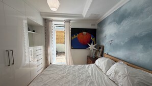 Ein Schlafzimmer mit einem Bett, einem Schminktisch, einem Nachttisch und einem Bild an der Wand.