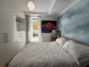 A bedroom with a bed, a dresser, a nightstand, and a painting on the wall. - Beautiful 2BDR Home Right by Regents Park (Greater London)