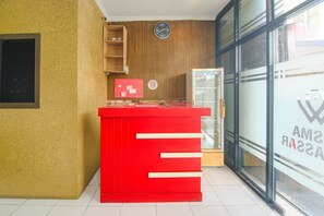 A reception area with a red counter, a clock, and a glass door with a logo. - Cozy Double Escape W/ Free WiFi and Parking (Makassar)