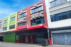 A multi-story building with commercial spaces on the ground floor, featuring large windows and air conditioning units. - Cozy Double Escape W/ Free WiFi and Parking (Makassar)