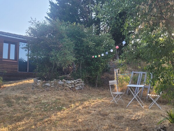 A backyard with a wooden deck, a stone wall, and a string of colorful lights.