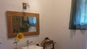 A bathroom with a wooden vanity, a white sink, a mirror, and a towel rack.