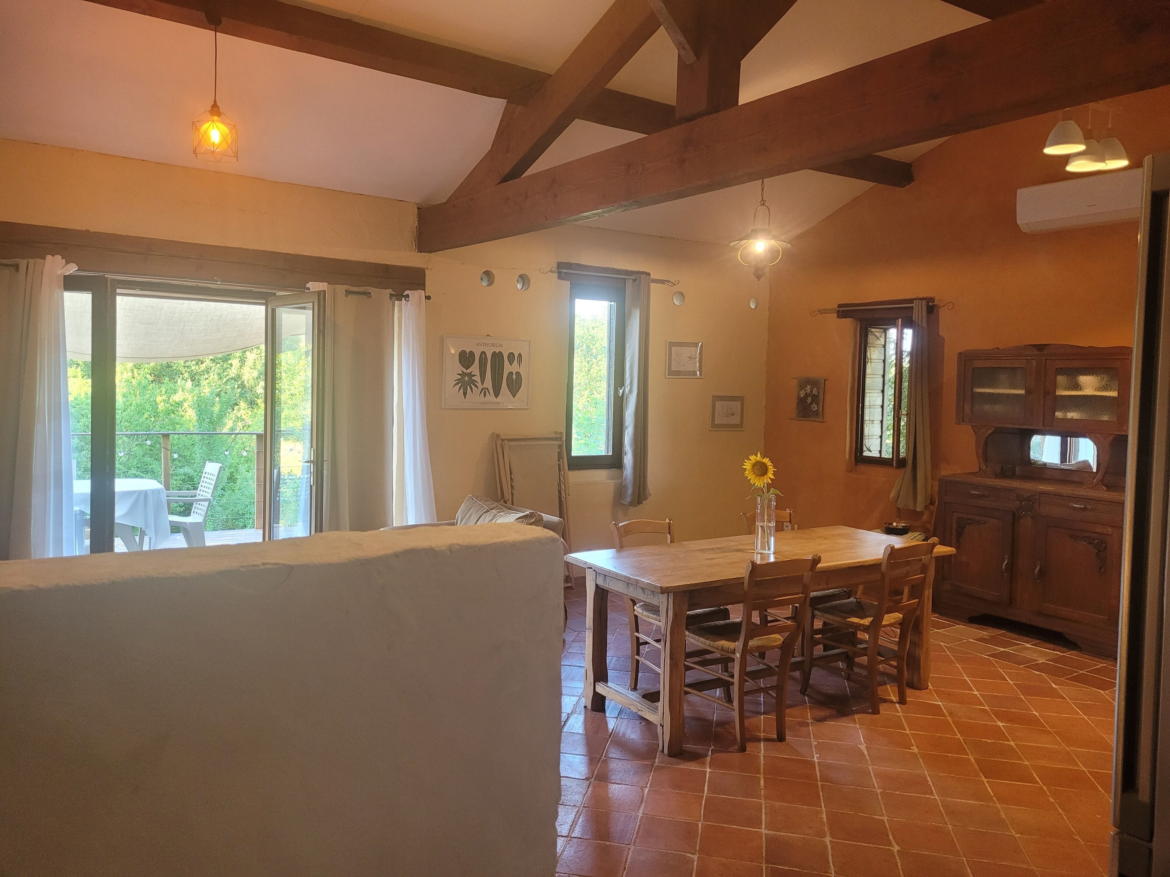 Un comedor con una mesa y sillas de madera, vistas al exterior y una cocina con armarios de madera.