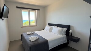 A bedroom with a bed, a window, a flat-screen TV, and a bedside table. - Brand-New Sea View in Vasto Marina with Parking (Marina di Vasto)
