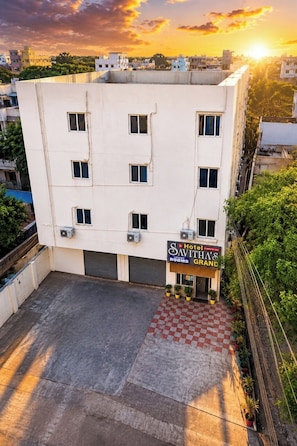 Un edificio de hotel con un letrero que dice 'Savitha's Luxury Rooms' y una zona de entrada a cuadros.