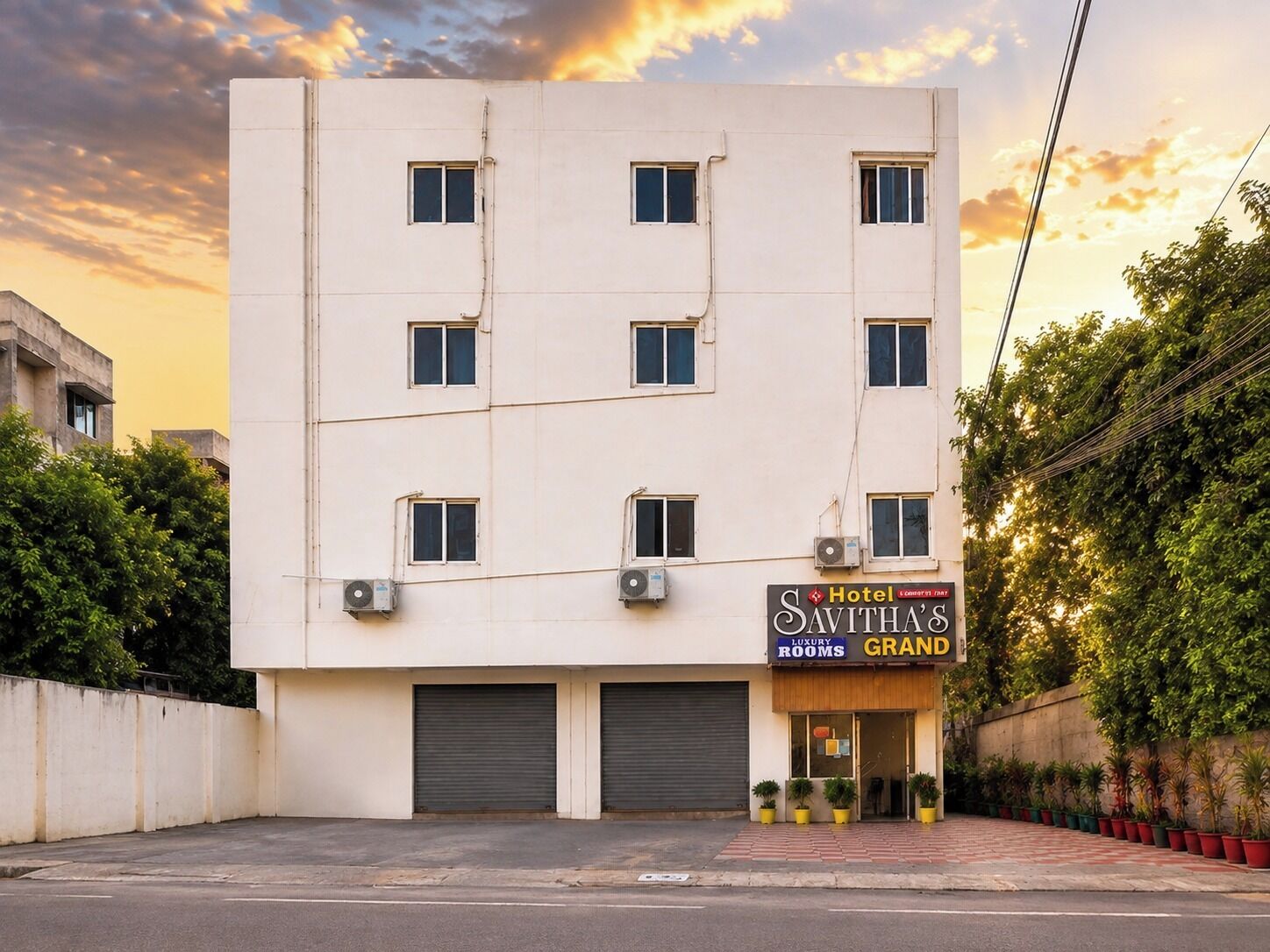 Un hotel de varios pisos con un cartel que indica 'Savitha's Grand', señalando habitaciones de lujo.