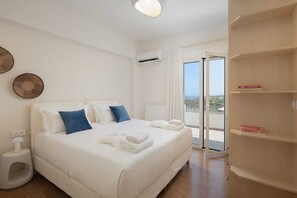 A hotel room with a bed, a bedside table, a window with a view, and a built-in shelf with books.