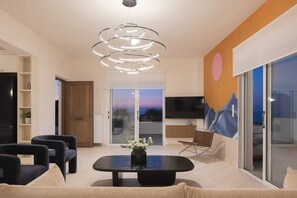A modern living room with a black coffee table, sofas, a TV, and a large window.
