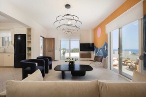 A modern living room with a sofa, chairs, a coffee table, and a TV.