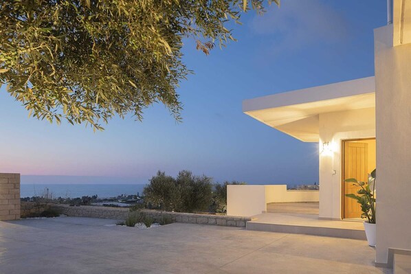 A modern house with a balcony overlooking a body of water.